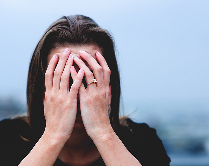 Woman covering face with hands, appearing stressed about hiking activities. Woman covering face with hands, appearing stressed about hiking activities.