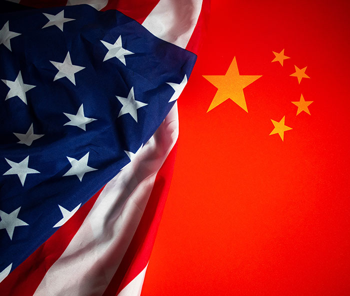 US and China flags overlap, symbolizing trade tension and tariffs. US and China flags overlap, symbolizing trade tension and tariffs.