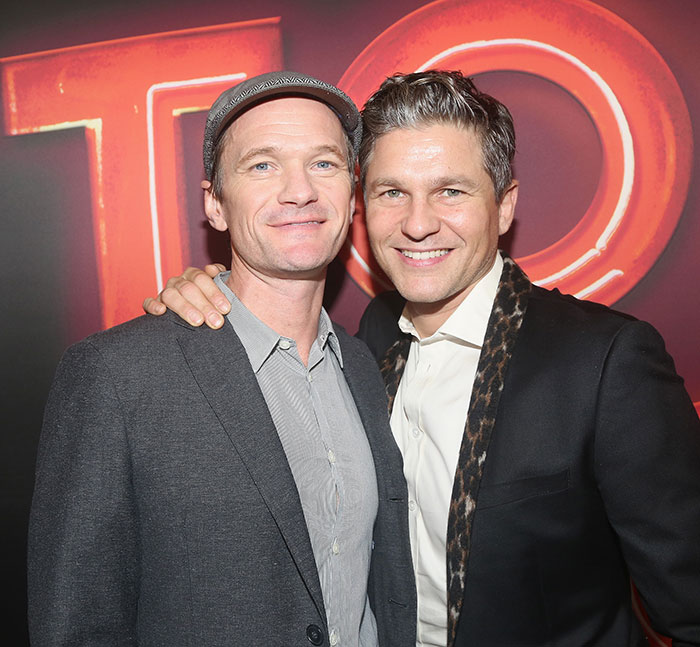 Two smiling men pose together at an event, wearing suits. Two smiling men pose together at an event, wearing suits.