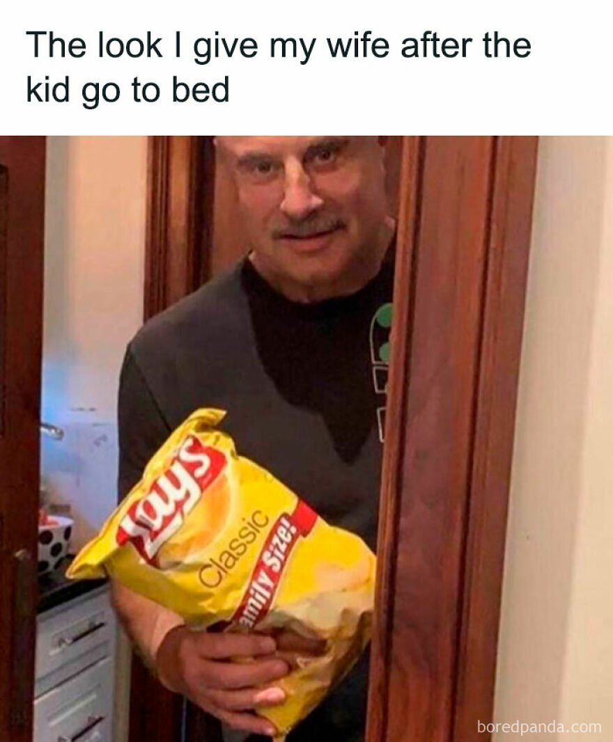 Man in doorway with chips, humorous expression about parenthood joy.