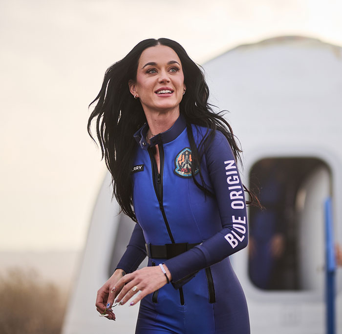 Person in Blue Origin spacesuit, outdoors, with futuristic setting in background. Person in Blue Origin spacesuit, outdoors, with futuristic setting in background.