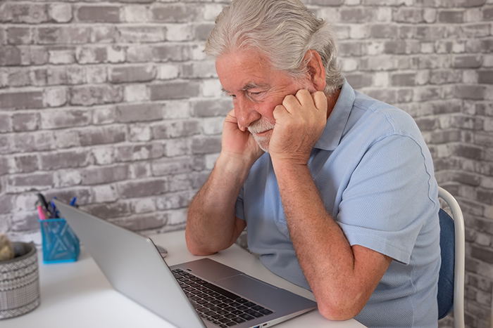 Elderly father looking at laptop, worried about vacation house security cameras. Elderly father looking at laptop, worried about vacation house security cameras.