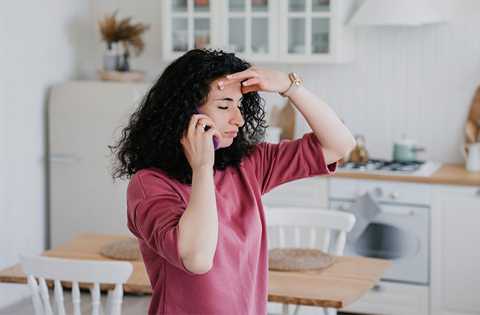 Woman on phone appearing stressed in a kitchen, related to neighbors in her late mom's house. Woman on phone appearing stressed in a kitchen, related to neighbors in her late mom's house.