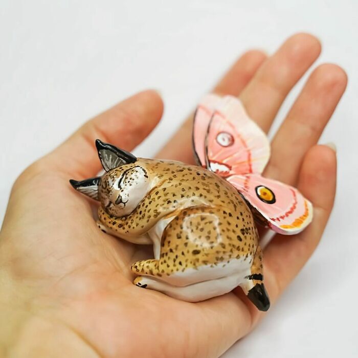 Hand holding an adorable pocket-sized animal figurine with butterfly wings, created by Vallavica.
