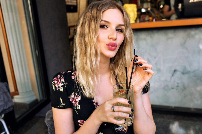 Blonde woman in floral dress sipping a drink with two straws, representing guys slept married woman why concept.