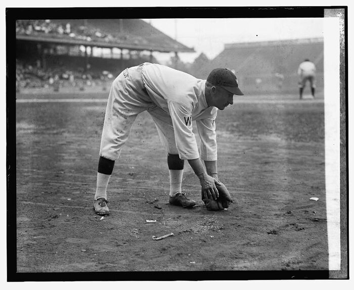 Vintage black and white rare photograph of a baseball player fielding the ball on a dirt field from glass negatives.
