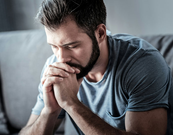 Man looking stressed while sitting on a couch after boss canceled doctor's appointment. Man looking stressed while sitting on a couch after boss canceled doctor's appointment.