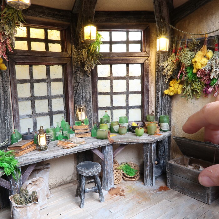 Miniatures by Tamar Cohen feature a detailed, rustic room with jars and dried flowers, evoking tiny worlds of wonder.