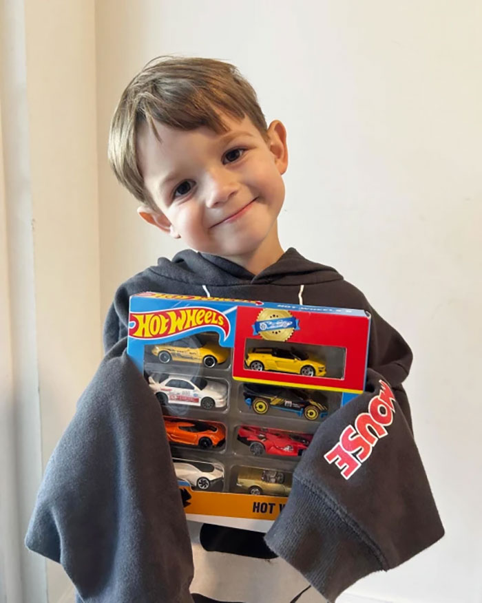 Child smiling with Hot Wheels cars, celebrating birthday surprise from local sports car lovers. Child smiling with Hot Wheels cars, celebrating birthday surprise from local sports car lovers.