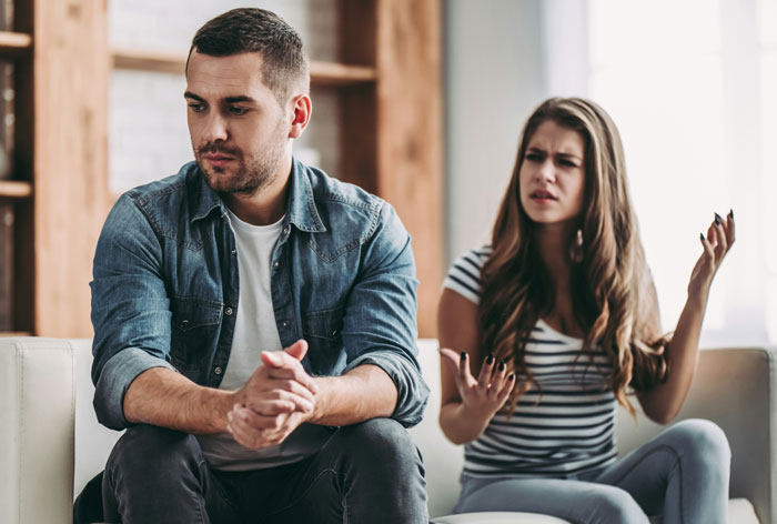 Man and woman on a sofa, woman expressing frustration, man looking away. Man and woman on a sofa, woman expressing frustration, man looking away.