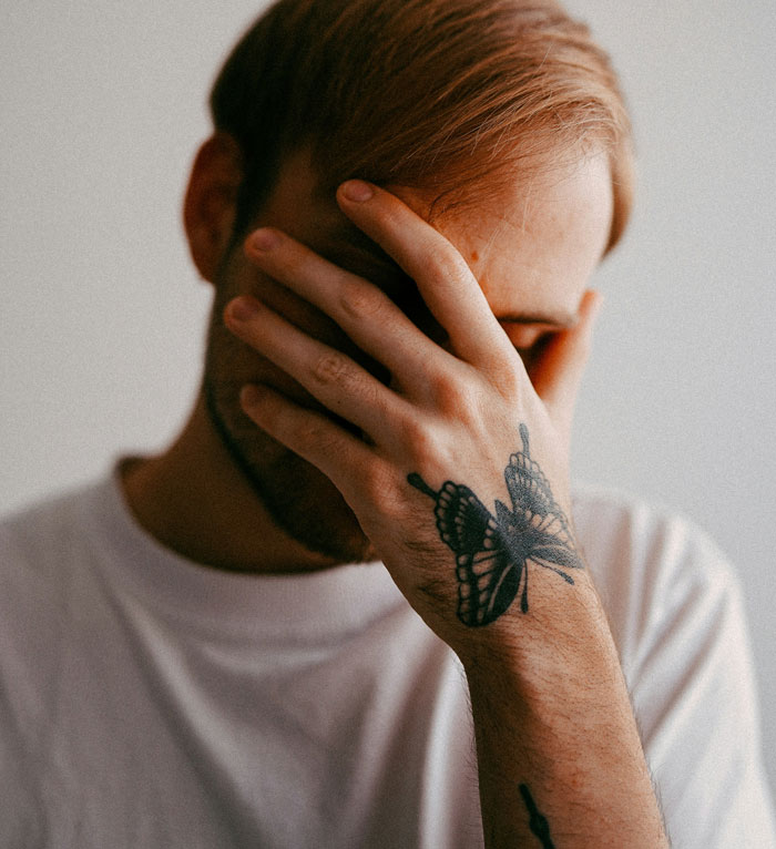 Man with butterfly tattoo covering face, illustrating emotions tied to family and vaccine updates. Man with butterfly tattoo covering face, illustrating emotions tied to family and vaccine updates.