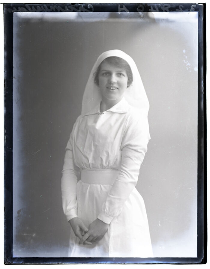 Black and white rare photograph of a smiling nurse in vintage uniform rescued from glass negatives.