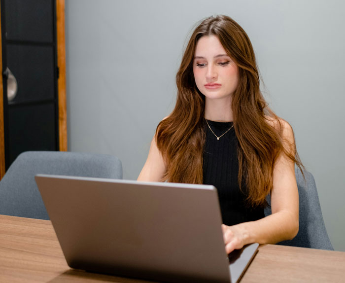 Young woman at a desk using a laptop, concerned about a canceled doctor's appointment. Young woman at a desk using a laptop, concerned about a canceled doctor's appointment.