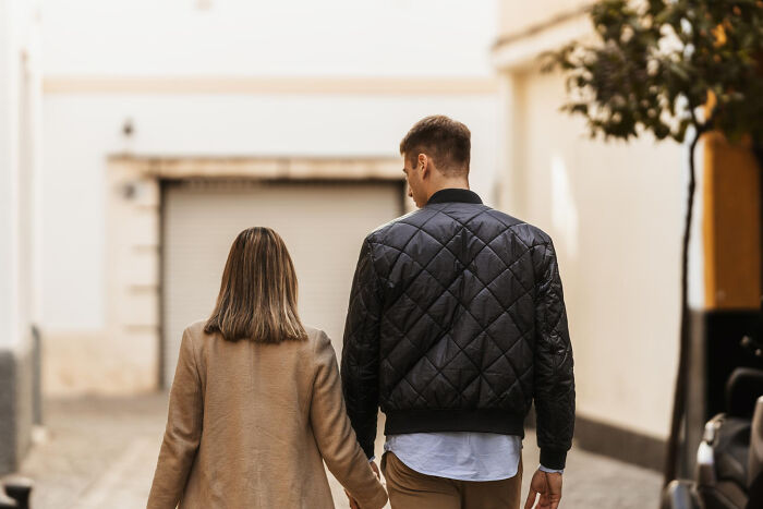 A woman and a man walking hand-in-hand down a street, highlighting differences in dating experiences.