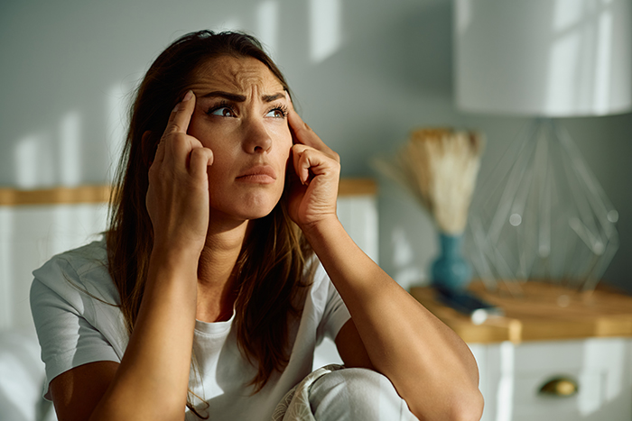 Woman deep in thought, expressing concern, in a sunlit room regarding MIL jokes about birth control. Woman deep in thought, expressing concern, in a sunlit room regarding MIL jokes about birth control.