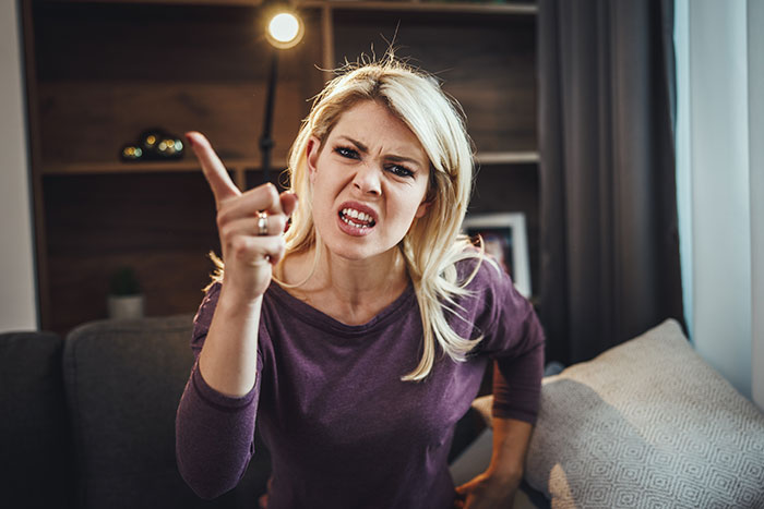 A woman angrily pointing and speaking in a living room setting. A woman angrily pointing and speaking in a living room setting.