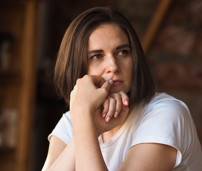Woman in deep thought, resting her head on her hand, wearing a white shirt indoors. Woman in deep thought, resting her head on her hand, wearing a white shirt indoors.
