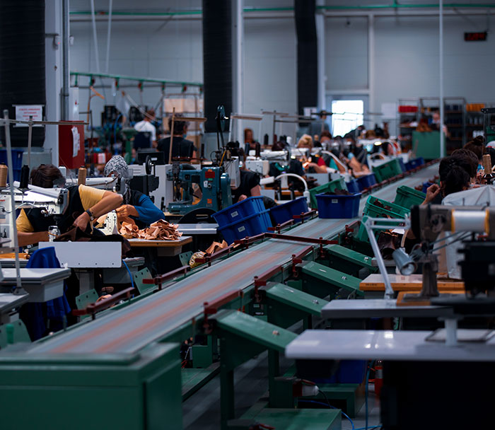 Workers in a large factory setting, assembling products, representing the impact of US tariffs. Workers in a large factory setting, assembling products, representing the impact of US tariffs.