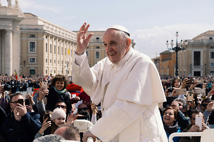 I don't know who this is, but the alt text could be: "Religious leader waving to a cheering crowd outdoors with historic buildings in the background. I don't know who this is, but the alt text could be: "Religious leader waving to a cheering crowd outdoors with historic buildings in the background.