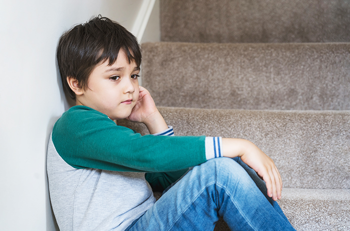 Child sitting on stairs, wearing a green and gray shirt, looking thoughtful, related to a dad's dilemma about support. Child sitting on stairs, wearing a green and gray shirt, looking thoughtful, related to a dad's dilemma about support.