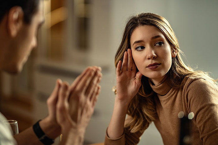 Woman listening intently during a discussion, representing roommate dispute over cheese. Woman listening intently during a discussion, representing roommate dispute over cheese.