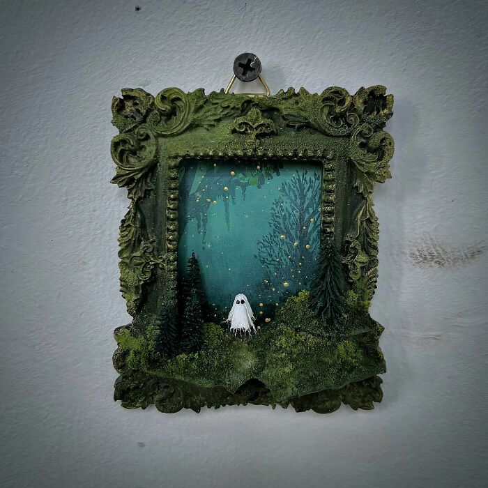 Intricate diorama by Caroline Dewison featuring a ghost in a mystical forest setting, surrounded by a decorative frame.