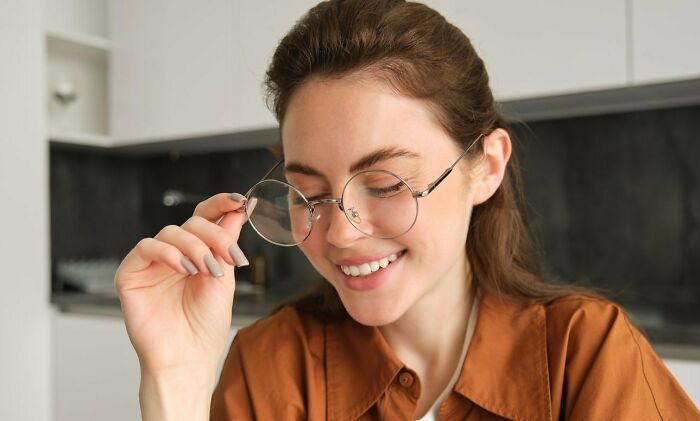 Woman smiling while adjusting glasses, showcasing mastery of playful insults.