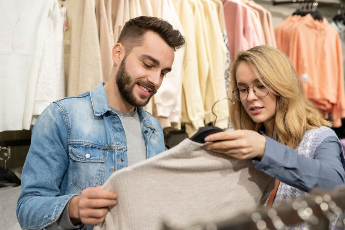 Man and woman shopping together, examining clothing in a store.