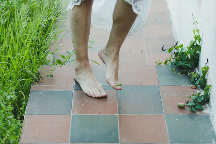 Barefoot person walking on tiled floor near green plants, illustrating a super normal thing in the country setting.