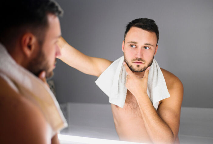 Man with towel looking in mirror, reflecting on common assumptions about women.