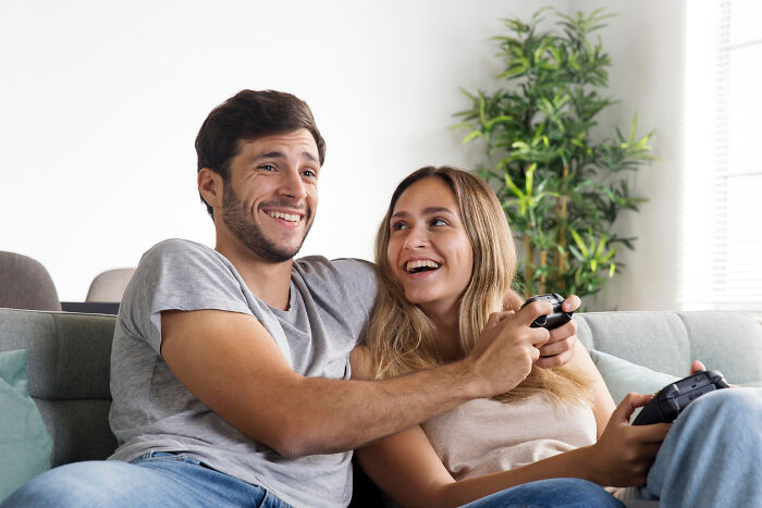 Smiling couple playing video games together, challenging common assumptions about women.