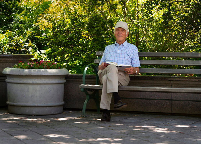 Elderly man enjoying a sunny day on a park bench, highlighting realities of aging.