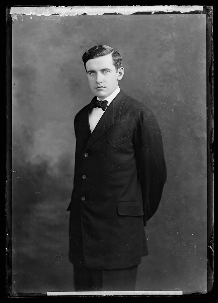 Young man in formal suit and bow tie posing for a rare photograph rescued from glass negatives, history restored.