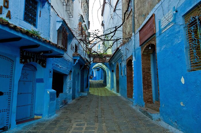 A colorful blue street scene in Chefchaouen, Morocco, resembling a real-life painting.