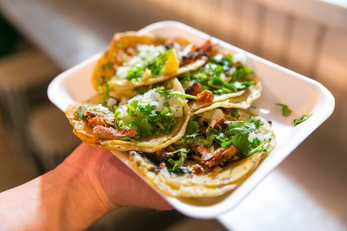 Plate of tacos with cilantro and onions, showcasing a top dish from different countries.