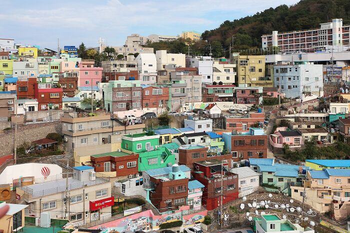 Colorful cityscape with vibrant houses stacked on a hillside, resembling a real-life painting.