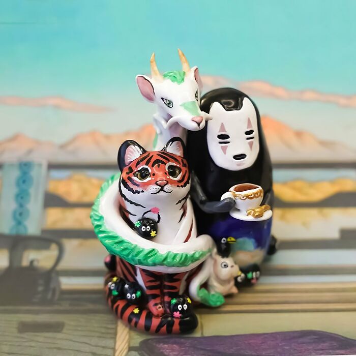 Pocket-sized animal figurines by Vallavica, featuring a tiger, dragon, and character holding a teacup, set against a scenic backdrop.