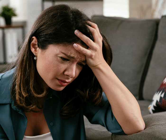 Woman looking upset on a couch, holding her head after breastfeeding discussion. Woman looking upset on a couch, holding her head after breastfeeding discussion.