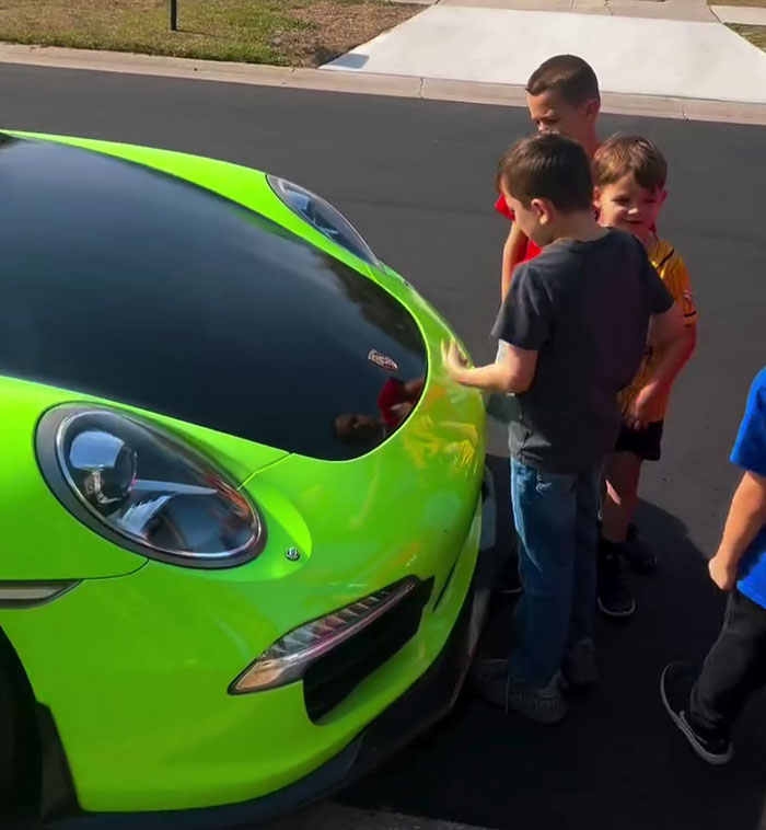 Children admiring a bright green sports car parked on the street. Children admiring a bright green sports car parked on the street.