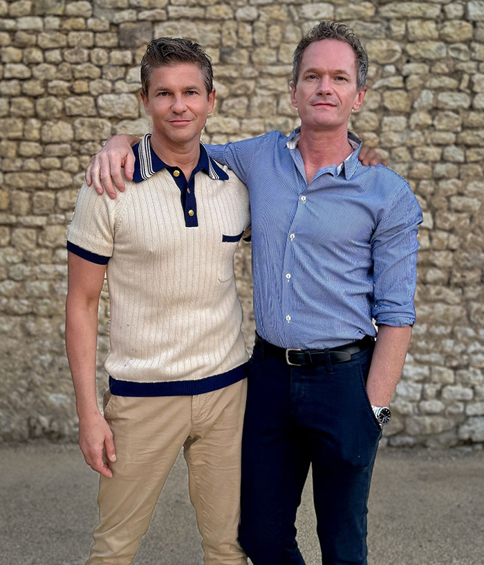 Two adults posing together in casual attire against a stone wall backdrop. Two adults posing together in casual attire against a stone wall backdrop.