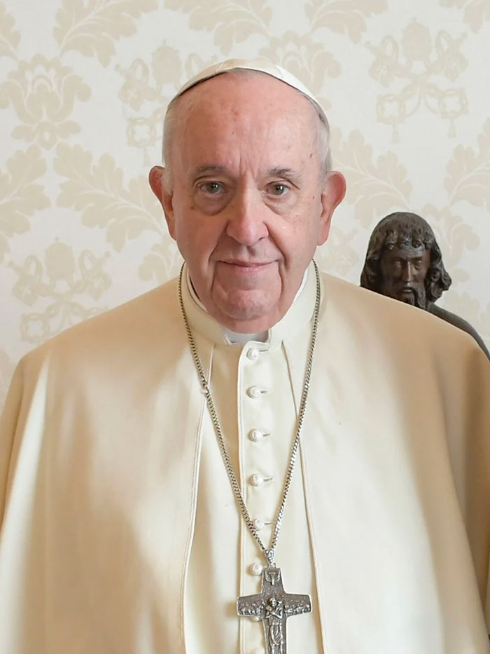 Pope Francis standing in traditional attire, with a solemn expression, wearing a cross necklace. Pope Francis standing in traditional attire, with a solemn expression, wearing a cross necklace.