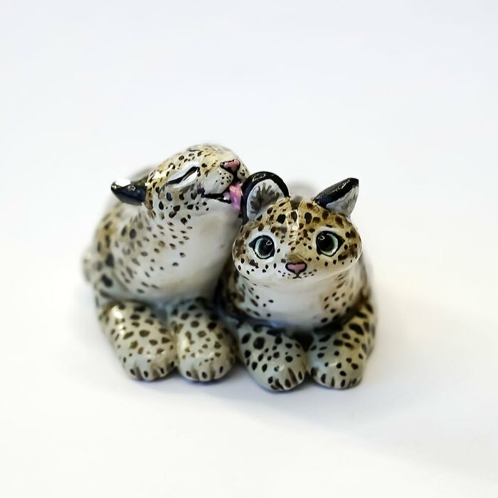 Adorable pocket-sized animal figurines of two leopards, one licking the other, crafted by Vallavica.