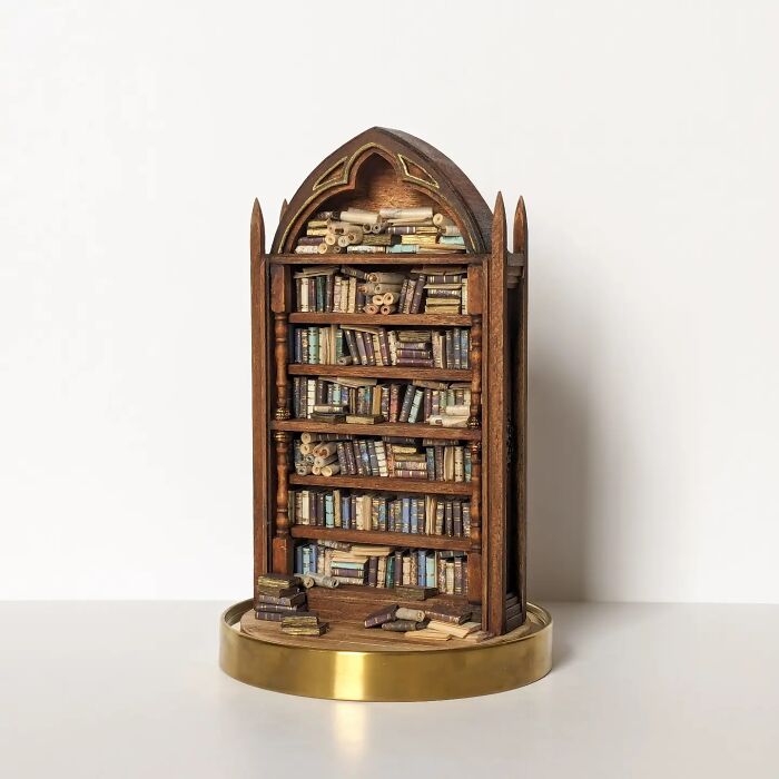 Miniature bookshelf with tiny books and scrolls by Tamar Cohen, creating a mesmerizing tiny world.