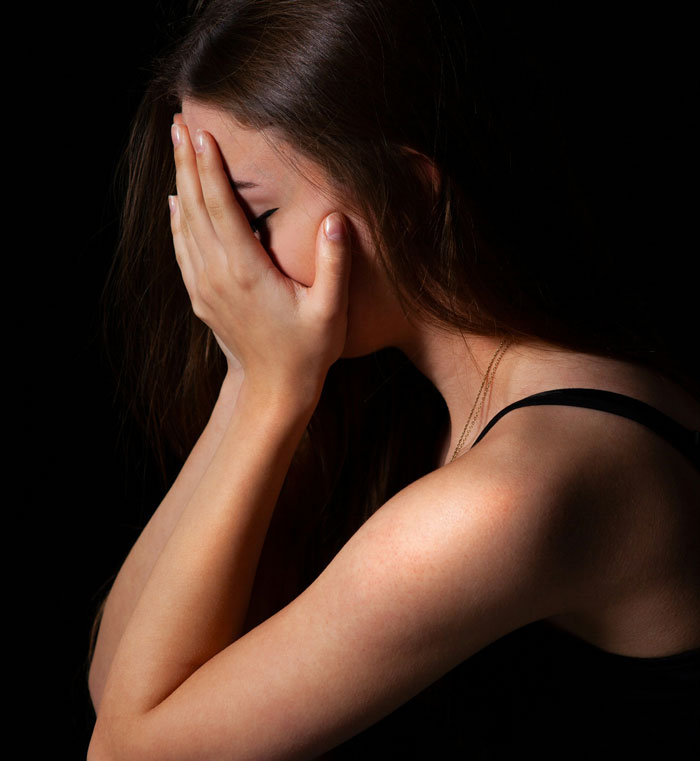 A woman covers her face in shock, reacting to unexpected family DNA results in a dimly lit room. A woman covers her face in shock, reacting to unexpected family DNA results in a dimly lit room.