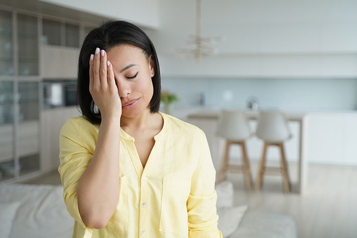 Woman in a yellow shirt looking frustrated in a modern living room. Woman in a yellow shirt looking frustrated in a modern living room.