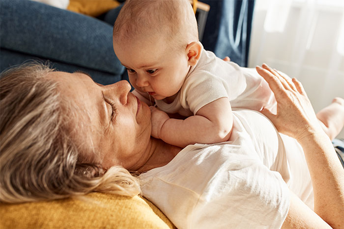 Grandmother and baby on couch, interacting closely, reflecting family boundaries and relationships. Grandmother and baby on couch, interacting closely, reflecting family boundaries and relationships.