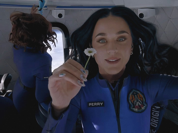 Person in Blue Origin suit with floating hair and holding a daisy, linked to flight conspiracy discussions. Person in Blue Origin suit with floating hair and holding a daisy, linked to flight conspiracy discussions.