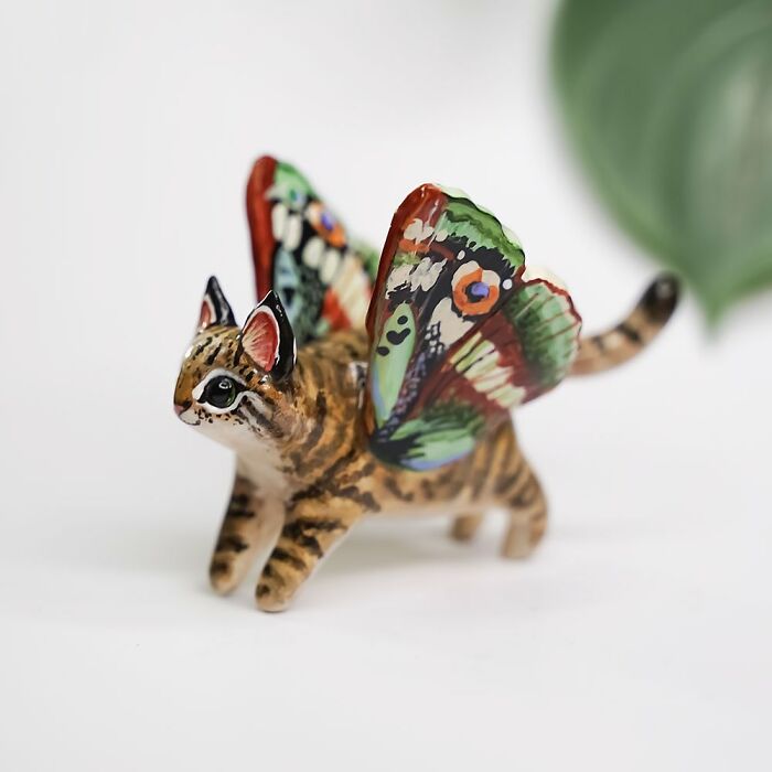 Pocket-sized animal figurine by Vallavica, featuring a cat with colorful butterfly wings.