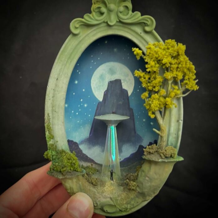 Alien diorama by Caroline Dewison, featuring a UFO, night sky, and miniature figure within an ornate frame.