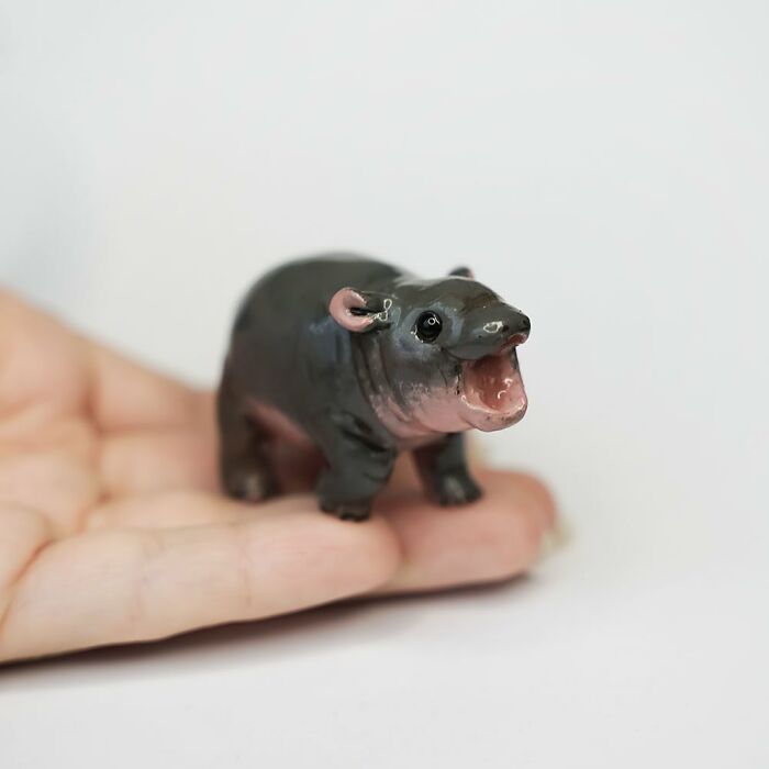 A pocket-sized animal figurine by Vallavica, resembling a tiny hippo, held in an open hand.